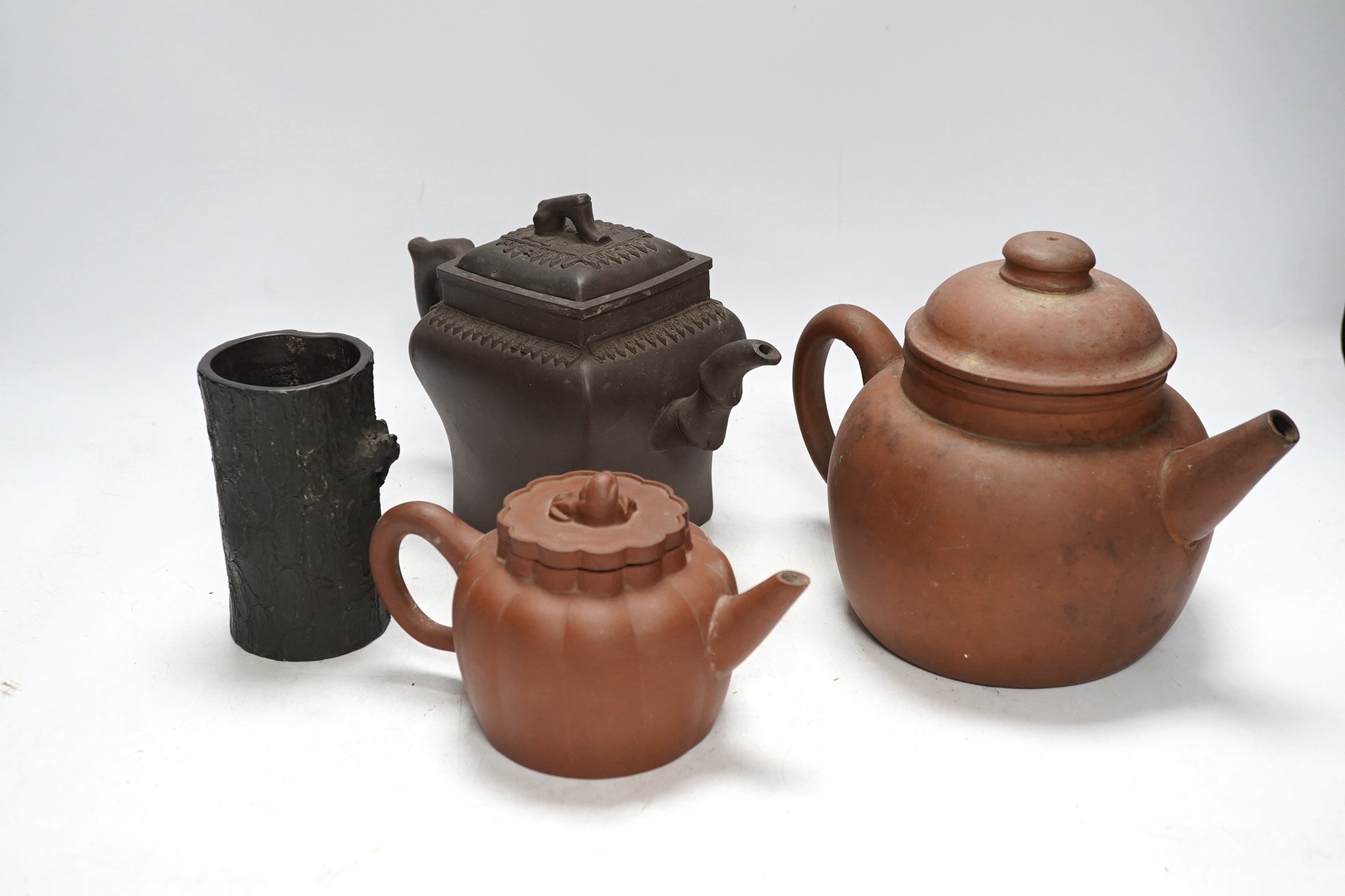 A 19th century Chinese Yixing pottery ‘tree trunk’ brush pot and three similar teapots, tallest 15cm. Condition - fair to good